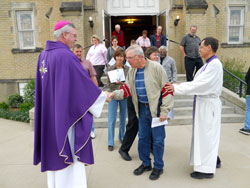 Bishop Christopher J. Coyne and Father Steven Schaftlein greet parishioners as they leave Mass at St. Francis Xavier Church in Henryville on March 25. The bishop pledged the archdiocese’s long-term assistance to the parish and community as they rebuild from the destructive March 2 tornadoes. (Photo by Patricia Happel Cornwell)