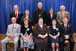 Two individuals, two married couples and two communities of religious sisters received Spirit of Service Awards during the April 26 dinner in Indianapolis. Award recipients, seated from left, are Pat Jerrell, Elaine Jerrell, St. Francis of Perpetual Adoration Sister M. Angela Mellady, Mary Pitzer and Fred Pitzer. Standing, from left, are award recipients William Spangler and Daughter of Charity Sister Catherine Kelly with Bishop Christopher J. Coyne, keynote speaker Allison Melangton and award recipient Tom Egold. (Photo by Rob Banayote)