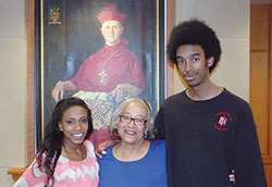 With two of her grandchildren by her side, Carole Finnell stands near a portrait of Cardinal Joseph E. Ritter, the man who changed her life and the course of Catholic education in the archdiocese by ordering the integration of Catholic schools in the late 1930s and early 1940s. She poses here in the library at Cardinal Ritter Jr./Sr. High School in Indianapolis with Brooke and Andrew Finnell, both students at the school. (Photo by John Shaughnessy)