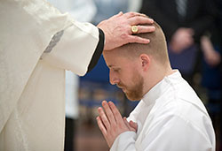 Archbishop Joseph W. Tobin ritually lays hands on seminarian Kyle Rodden during an April 11, 2015, diaconate ordination liturgy at the Archabbey Church of Our Lady of Einsiedeln in St. Meinrad. (Photo courtesy of Saint Meinrad Archabbey)