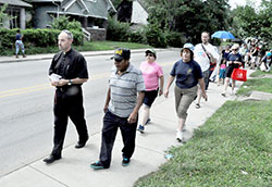 Father Christopher Wadelton, pastor of St. Philip Neri Parish in Indianapolis, leads a group in praying the rosary on July 10 while walking through the neighborhood surrounding the faith community on the city’s near east side. The parish is sponsoring a series of nine consecutive prayer walks in response to increased drug problems and violent crimes in its neighborhood. (Photo by Sean Gallagher)