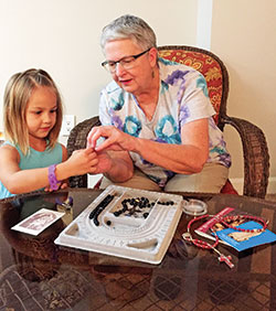 Peggy Frey of SS. Peter and Paul Cathedral Parish in Indianapolis shows her 5-year-old great-niece Clara Messier how to make a rosary. (Submitted photo by Tony Messier)