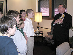 Archbishop Daniel M. Buechlein, right, shows a special edition of the Catechism of the Catholic Church to a group of students from St. Pius X School in Indianapolis during a visit on Jan. 27, 2009, to his office in the Archbishop Edward T. O’Meara Catholic Center in Indianapolis. Archbishop Buechlein played a significant role in the renewal of catechesis in the U.S. while serving as chairman of the U.S. bishops’ Ad Hoc Committee on the Use of the Catechism of the Catholic Church. (File photo by Sean Gallagher)