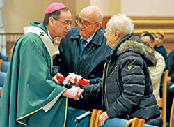 Archbishop Charles C. Thompson gives a gift to Leo and Margaret Hartman on Feb. 10 during the archdiocesan World Marriage Day Mass at SS. Peter and Paul Cathedral in Indianapolis. Members of Holy Name of Jesus Parish in Indianapolis, the Hartmans have been married for 68 years. (Photo by Sean Gallagher)