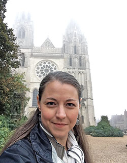 Jennifer Brandon poses in front of fog-enshrouded Chartres Cathedral in France. The music teacher at St. Matthew the Apostle School in Indianapolis visited the cathedral as part of her travels for a book she is co-authoring, Places of Light: The Gift of Cathedrals to the World. (Submitted photo)
