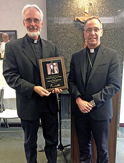 Father Guy Roberts, pastor of St. Joan of Arc Parish in Indianapolis, poses with Archbishop Charles C. Thompson after the archbishop presented him with Catholic Radio Indy’s first-ever Archbishop Fulton Sheen Evangelist of the Year award in the organization’s Indianapolis office on Sept. 9. (Photo by Natalie Hoefer)