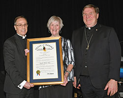 Archbishop Charles C. Thompson and Cardinal Joseph W. Tobin of Newark, N.J. (formerly the archbishop of Indianapolis) share smiles with archdiocesan chancellor Annette “Mickey” Lentz as she holds the Sagamore of the Wabash, the state of Indiana’s highest honor, during the archdiocese’s inaugural Legacy Gala, held in person at the JW Marriott in Indianapolis and via livestream on April 16. The two archbishops and Lentz have each received full doses of a coronavirus vaccine. (Submitted photo by Rob Banayote)