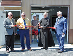 Father John Hollowell, pastor of Annunciation Parish in Brazil, prepares to cut a ribbon during an opening ceremony for the parish’s new St. Vincent de Paul food pantry building on April 23. Holding the ribbon are Larry Tempel, left, Brazil Mayor Brian Wyndham and Patrick Hardman, president of the Annunciation Parish St. Vincent de Paul conference in Brazil. (Photo by Natalie Hoefer)