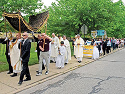 Father Christopher Wadelton carries the Blessed Sacrament in a monstrance at the head of a May 7 eucharistic procession on the grounds of St. Bartholomew Parish in Columbus. (Photo by Sean Gallagher)