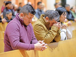 César, a la izquierda, Julio y Margarita Zúñiga se arrodillan en oración durante una misa celebrada el 3 de noviembre en la Iglesia de Santa Rita de Indianápolis en honor a San Martín de Porres, patrón de la justicia racial. (Fotografía de Sean Gallagher)