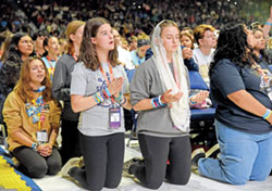 Teens kneel in prayer during eucharistic adoration on Nov. 17 in Lucas Oil Stadium in Indianapolis during the National Catholic Youth Conference. Among the teens is Zowie Pierce, in a gray T-shirt at left, of Our Lady of the Greenwood Parish in Greenwood. (Photo by Sean Gallagher)