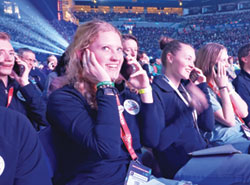 In the foreground, Grace Stecker of the Diocese of Helena, Mont., smiles with joy as she calls her dad to tell her she loves him. She and the more than 12,000 National Catholic Youth Conference (NCYC) participants were asked by a speaker to call someone with a message of love during the NCYC opening session in Lucas Oil Stadium in Indianapolis on Nov. 16. (Photo by Natalie Hoefer)