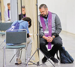 Father Noah Diehm of the Archdiocese of Dubuque, Iowa, hears the confession of a National Catholic Youth Conference participant on Nov. 17 in the Indiana Convention Center in Indianapolis. (Photo by Sean Gallagher)