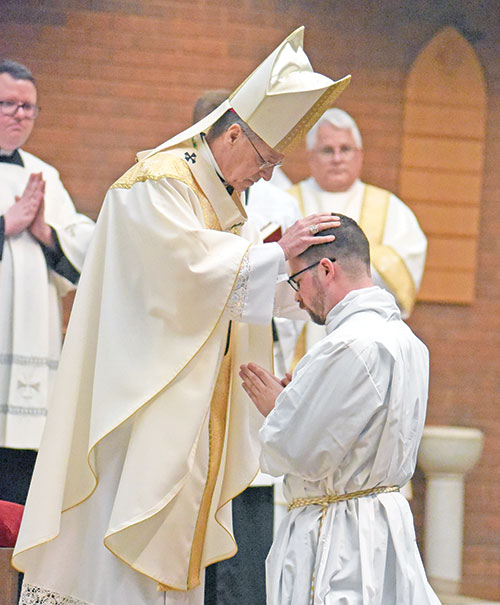 Archbishop Charles C. Thompson ritually lays his hands on the head of seminarian Liam Hosty while ordaining him a transitional deacon during an April 27 Mass at St. Barnabas Church in Indianapolis. (Photo by Sean Gallagher)
