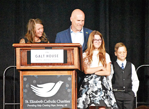 Clarissa and Wade Thaxton smile at their daughter Elanore, whom they adopted through St. Elizabeth Catholic Charities’ Adoption Bridges of Kentuckiana in New Albany, during their talk at St. Elizabeth’s Giving Hope-Changing Lives gala on April 18 in Louisville, Ky.  The Thaxton’s son Wesley stands at right. (Photos by Natalie Hoefer)