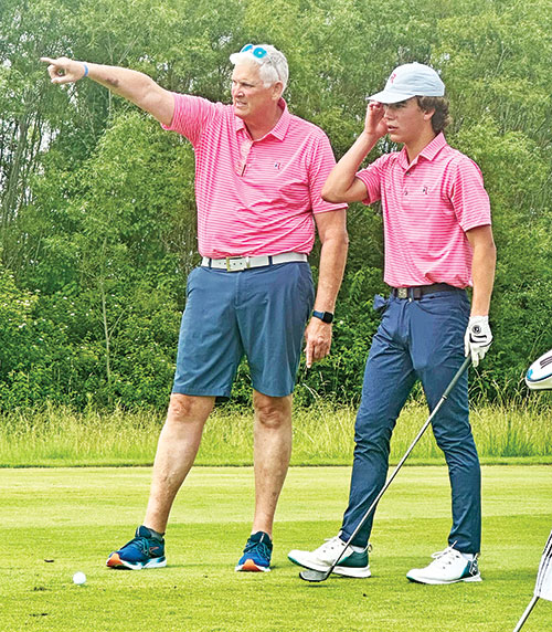As the co-head coach of the boys’ golf program at Roncalli High School in Indianapolis, Jim Poole works closely with his team members, including giving a tip to Noah Irwin, during this past season. (Submitted photo)