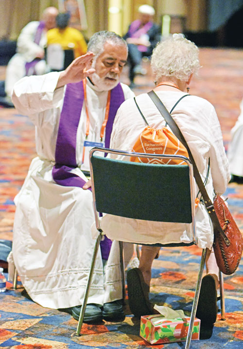 Father Joseph Moriarty gives absolution on July 17 in the sacrament of penance to a penitent attending the National Eucharistic Congress at the Indiana Convention Center in Indianapolis. (Photo by Sean Gallagher)