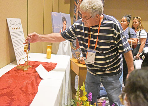 Anthony Trujillo of Albuquerque, N.M., places rosary against a reliquary holding part of the pericardium of Blessed Carlo Acutis on July 19 during the National Eucharistic Congress at the Indiana Convention Center in Indianapolis. (Photo by Sean Gallagher)