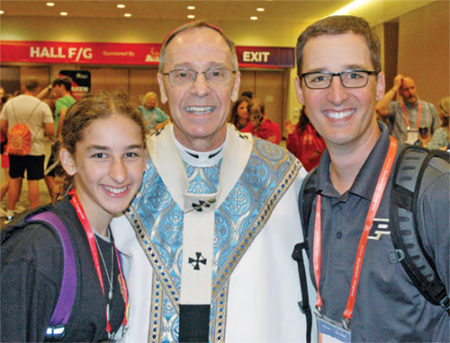 After celebrating a Mass on the morning of July 20 for youths at the National Eucharistic Congress in Indianapolis, Archbishop Charles C. Thompson greeted, blessed and smiled for photos with people for more than 30 minutes in a hallway of the Indiana Convention Center, taking his time with each group and person. Here, he poses for a photo with Maria Otte and her dad, Karl Otte, members of St. Simon the Apostle Parish in Indianapolis. (Photo by John Shaughnessy)