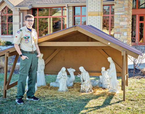 Michael Dexter, a member of Nativity of Our Lord Jesus Christ Parish in Indianapolis, poses by his faith community’s outdoor Nativity set. He created a new lightweight stable for it as part of an Eagle Scout project he completed. (Submitted photo)