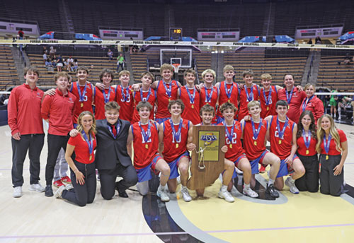 The players, coaches and managers of the boys’ volleyball team of Roncalli High School in Indianapolis are all smiles on May 31 at Mackey Arena in West Lafayette, Ind., as they celebrate winning the first Indiana High School Athletic Association’s state championship in the sport. (Photo courtesy of John Smith of Roncalli High School in Indianapolis)