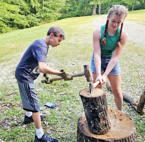 Jonas Burton, left, and Laila McMasters, both members of St. Agnes Parish in Nashville, work as a team to split wood for someone in need during St. Agnes’ Saints Training Camp, offered on June 25-29. (Submitted photo) 