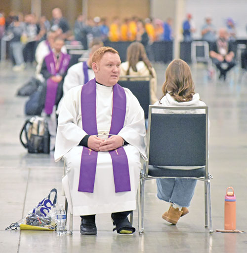 A priest hears a confession on Nov. 21 in an exhibit hall at the Indiana Convention Center in Indianapolis used for the sacrament of penance during the National Catholic Youth Conference. (Photo by Sean Gallagher)